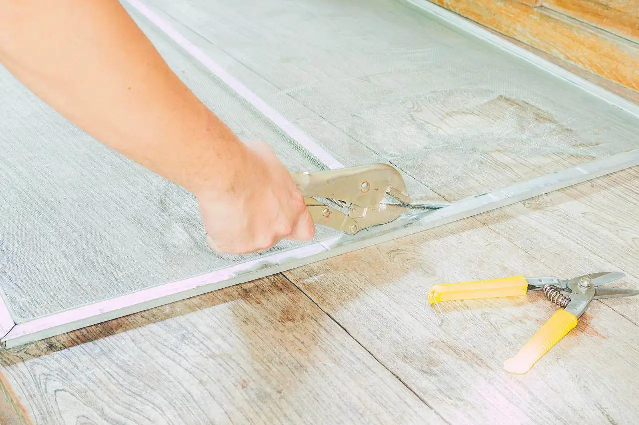 Professional tiler installing kitchen wall tiles using adhesive and spacers.